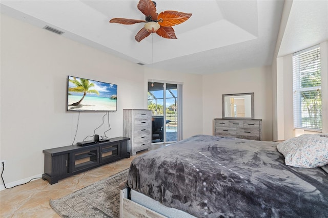 bedroom with access to exterior, a tray ceiling, visible vents, and multiple windows