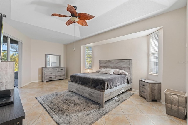 bedroom with baseboards, a tray ceiling, multiple windows, and access to exterior