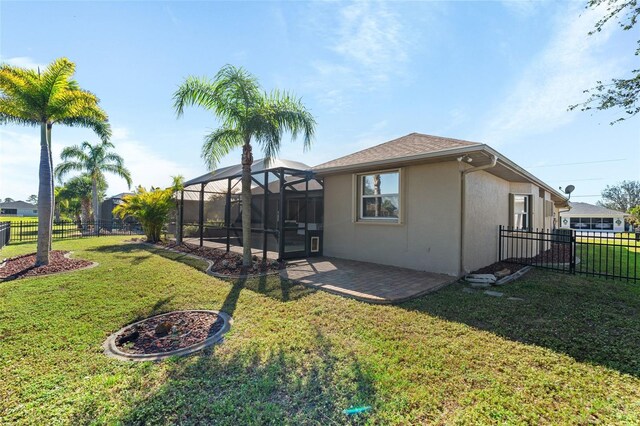 rear view of house with a fenced backyard, a lanai, a lawn, stucco siding, and a patio area