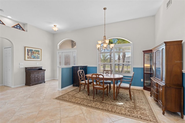 dining space with arched walkways, light tile patterned flooring, visible vents, and a notable chandelier