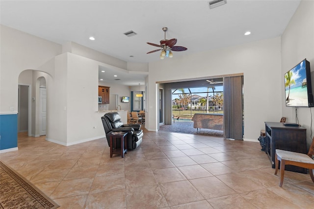 sitting room featuring a ceiling fan, arched walkways, visible vents, and baseboards