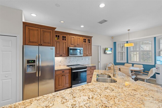 kitchen featuring brown cabinets, stainless steel appliances, visible vents, backsplash, and a sink