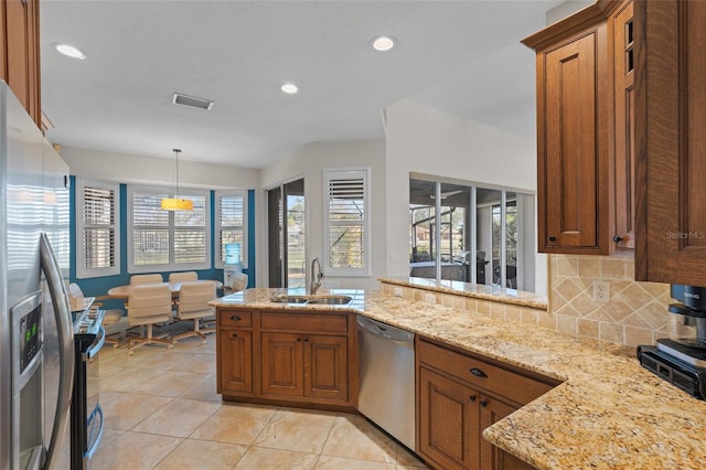 kitchen featuring brown cabinets, visible vents, backsplash, appliances with stainless steel finishes, and a sink