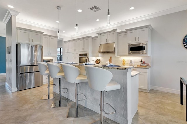 kitchen featuring tasteful backsplash, decorative light fixtures, a kitchen breakfast bar, a kitchen island, and stainless steel appliances