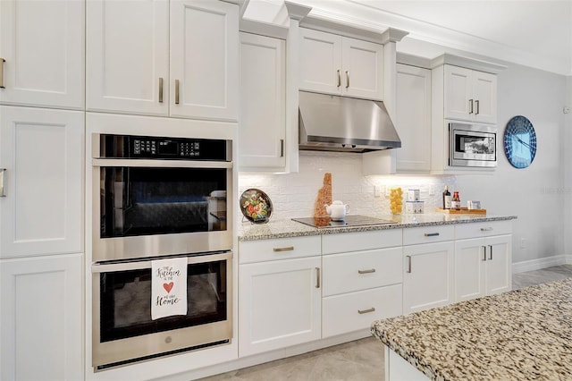 kitchen featuring stainless steel appliances, white cabinetry, light stone countertops, and tasteful backsplash