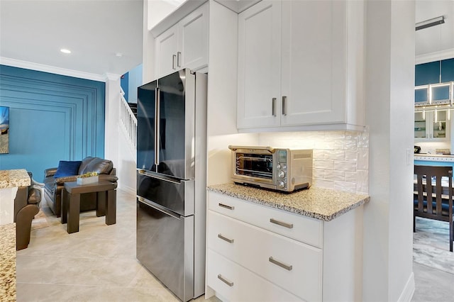 kitchen featuring tasteful backsplash, crown molding, refrigerator, light stone countertops, and white cabinets