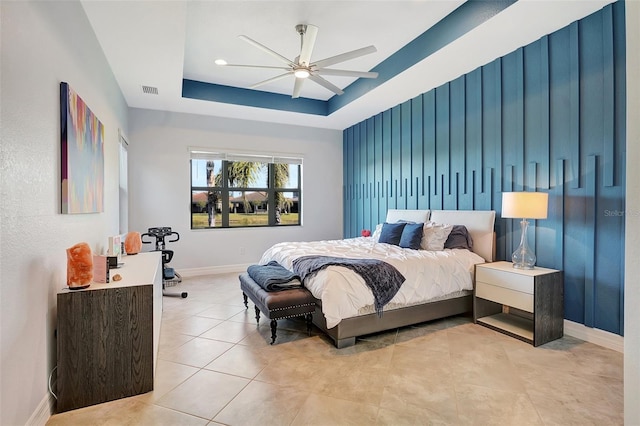 tiled bedroom with ceiling fan and a tray ceiling