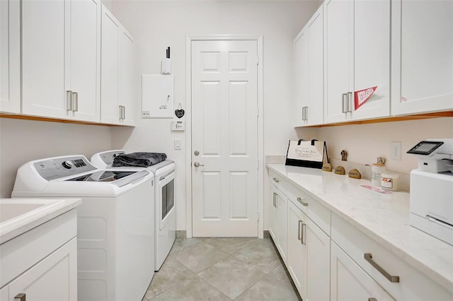 laundry area featuring light tile patterned floors, washer and clothes dryer, and cabinets