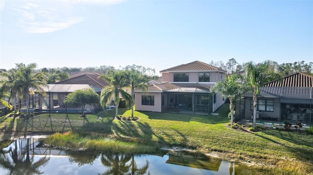 back of property featuring a water view, a yard, and a lanai