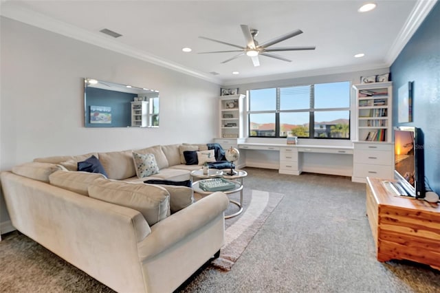 living room featuring ornamental molding, carpet floors, built in desk, and ceiling fan