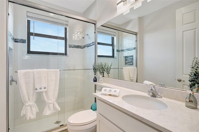 bathroom with a shower with door, vanity, and toilet