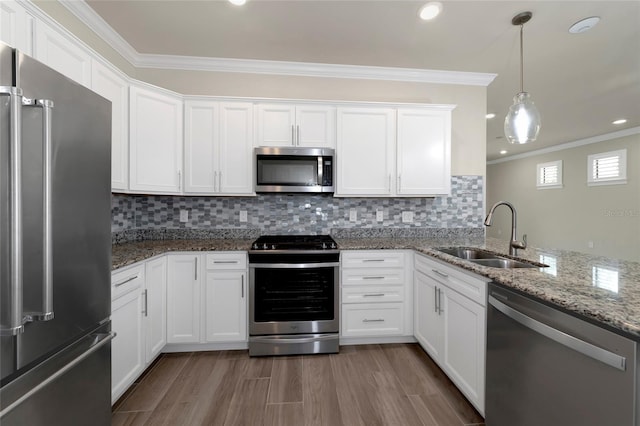 kitchen featuring crown molding, appliances with stainless steel finishes, wood finished floors, white cabinetry, and a sink