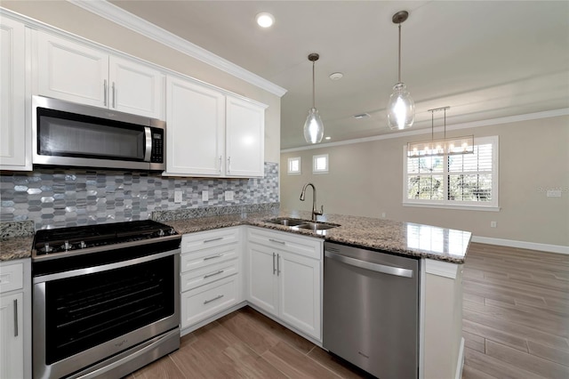 kitchen with crown molding, a peninsula, appliances with stainless steel finishes, and a sink