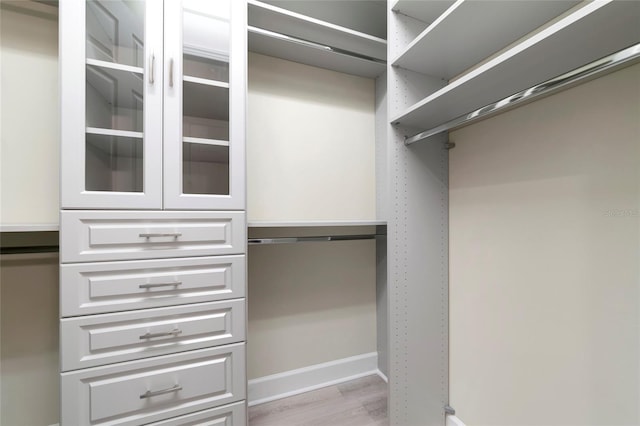 walk in closet with light wood-style floors