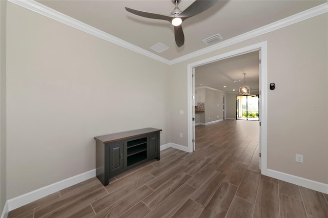 spare room with visible vents, crown molding, baseboards, wood tiled floor, and a ceiling fan