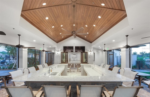 interior space with a kitchen bar, open floor plan, wooden ceiling, ceiling fan, and a large island with sink