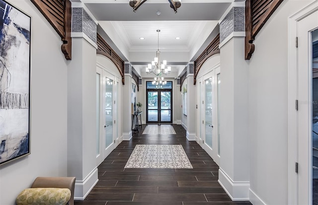 foyer entrance with ornamental molding, a chandelier, and french doors