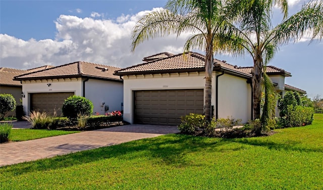 mediterranean / spanish-style home featuring stucco siding, a front yard, an attached garage, and a tiled roof