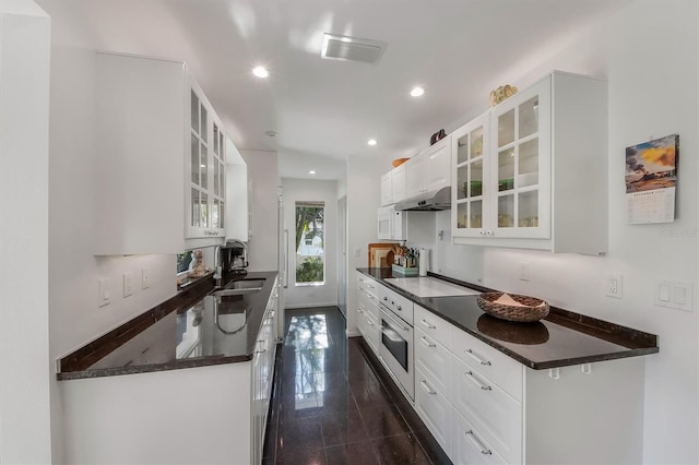 kitchen with sink, dark stone countertops, black electric cooktop, oven, and white cabinets