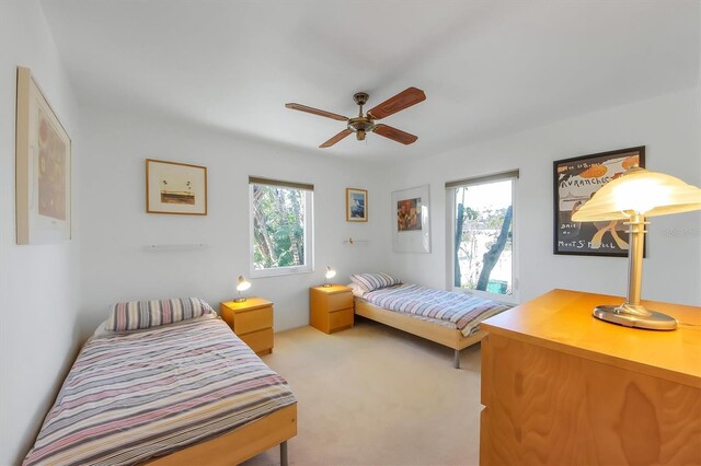 bedroom featuring multiple windows, light colored carpet, and ceiling fan