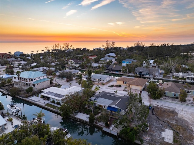 aerial view at dusk featuring a water view