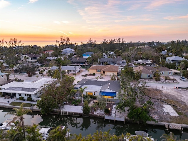 aerial view at dusk featuring a water view