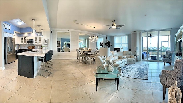 tiled living room with ceiling fan with notable chandelier and sink