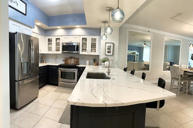 kitchen with pendant lighting, sink, appliances with stainless steel finishes, white cabinetry, and kitchen peninsula