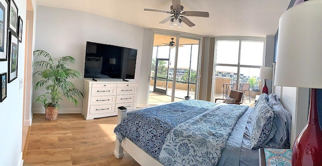 bedroom featuring multiple windows, a wall of windows, light hardwood / wood-style floors, and access to outside