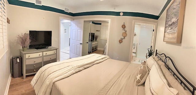 bedroom featuring connected bathroom and light wood-type flooring