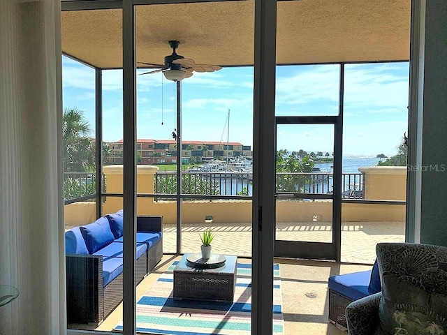 sunroom featuring a water view, plenty of natural light, and ceiling fan