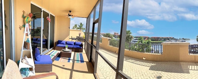 sunroom with ceiling fan and a water view