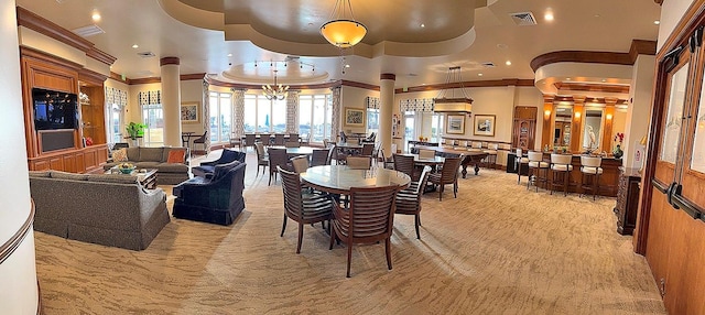 dining room featuring crown molding, light colored carpet, a raised ceiling, and ornate columns