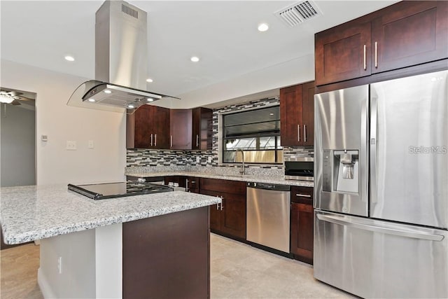 kitchen with a kitchen island, decorative backsplash, island exhaust hood, light stone counters, and stainless steel appliances