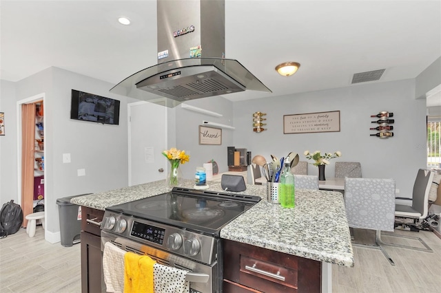 kitchen featuring light stone counters, island range hood, light hardwood / wood-style floors, and stainless steel electric range oven