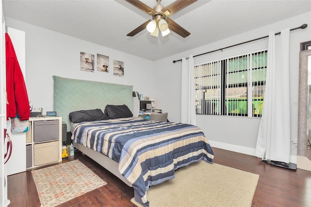 bedroom featuring dark wood-type flooring, ceiling fan, and a textured ceiling