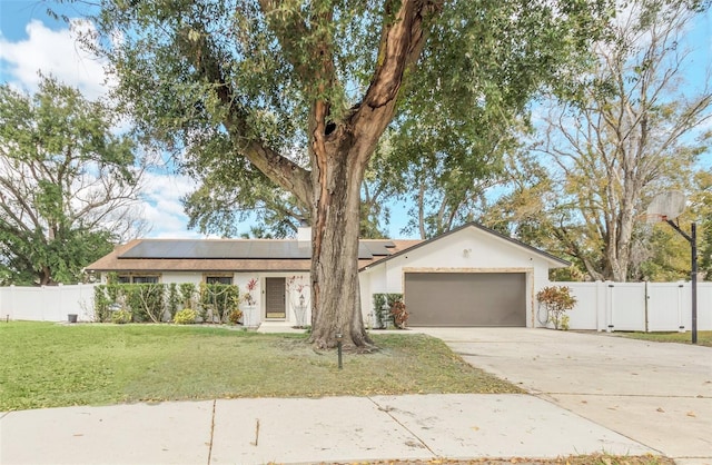 ranch-style home featuring a garage, a front yard, and solar panels