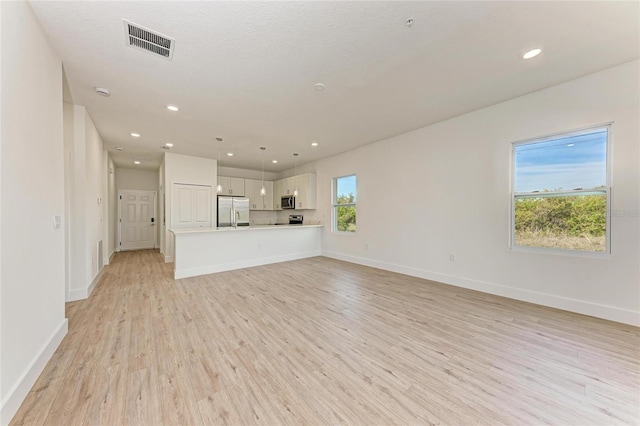 unfurnished living room featuring a textured ceiling and light hardwood / wood-style floors