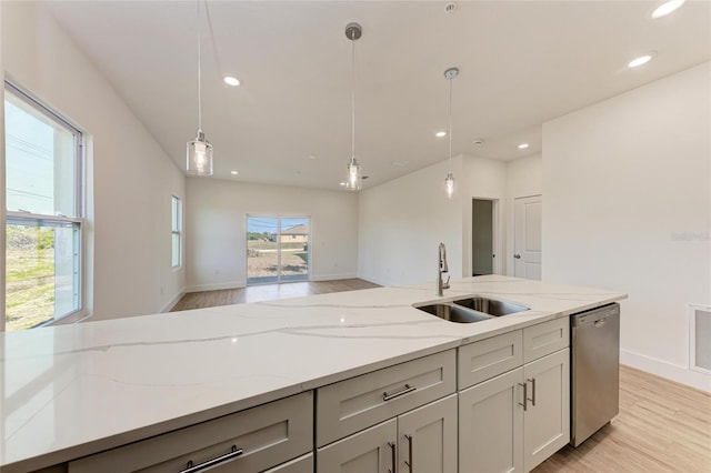 kitchen featuring sink, light stone counters, decorative light fixtures, light wood-type flooring, and dishwasher