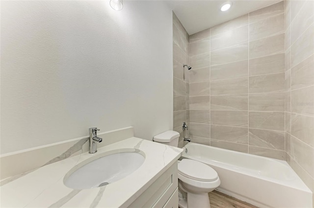 full bathroom with hardwood / wood-style floors, vanity, toilet, and tiled shower / bath