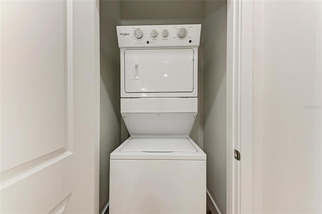 clothes washing area with stacked washing maching and dryer