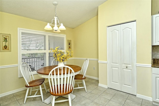 dining space featuring an inviting chandelier, lofted ceiling, light tile patterned flooring, and a textured ceiling