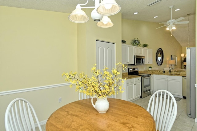 dining area featuring ceiling fan, sink, light tile patterned floors, and a textured ceiling