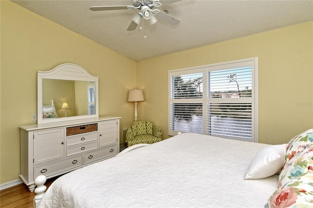 bedroom with ceiling fan, a textured ceiling, vaulted ceiling, and wood-type flooring