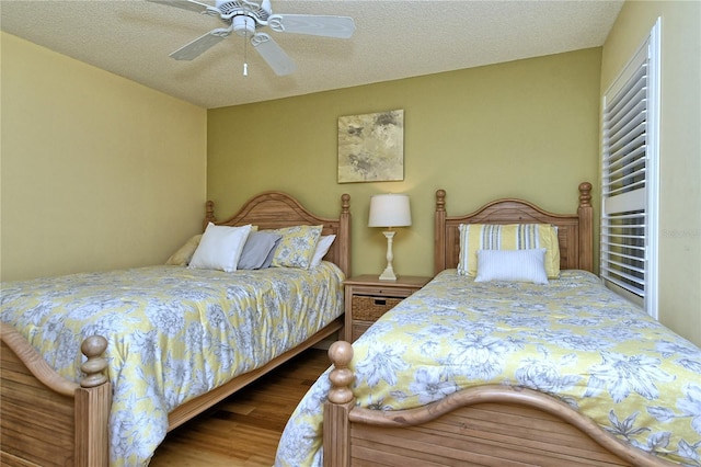 bedroom with ceiling fan, hardwood / wood-style floors, and a textured ceiling