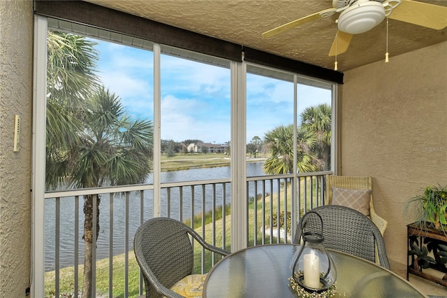 sunroom / solarium featuring plenty of natural light, ceiling fan, and a water view