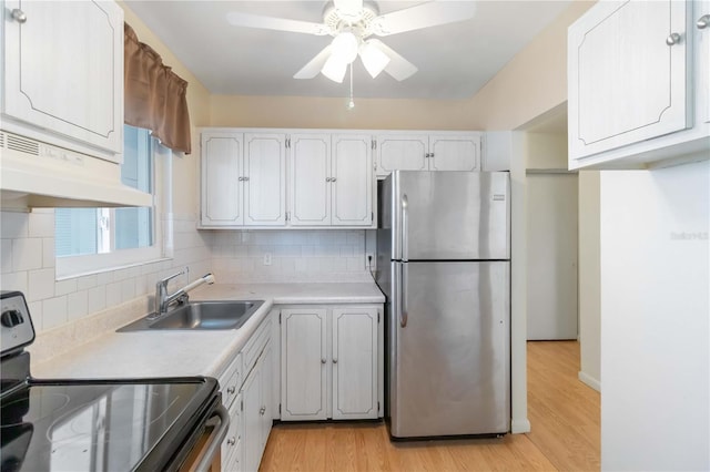 kitchen featuring sink, stainless steel appliances, tasteful backsplash, light hardwood / wood-style floors, and white cabinets