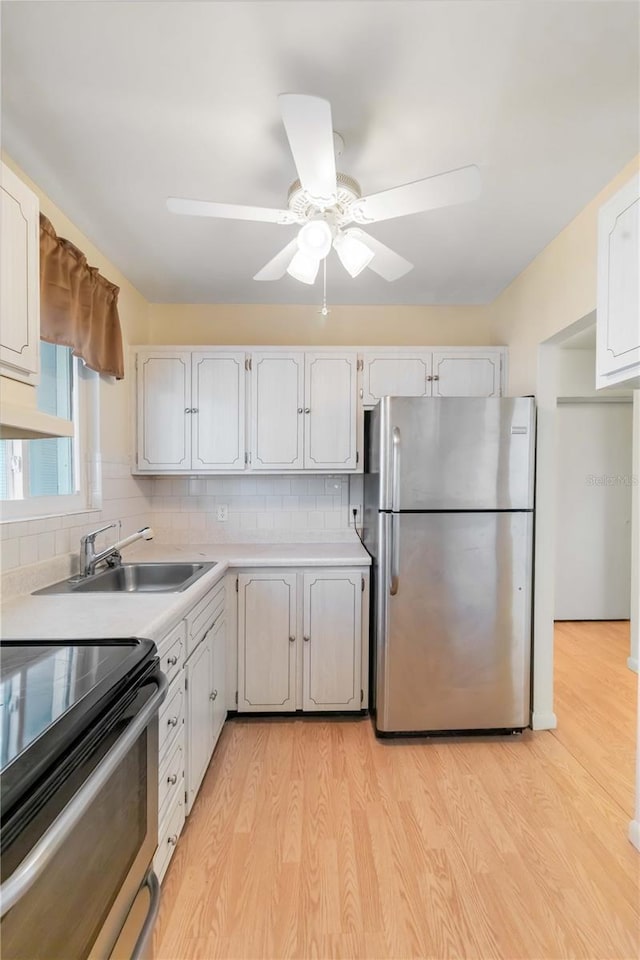 kitchen featuring tasteful backsplash, appliances with stainless steel finishes, white cabinets, and light wood-type flooring