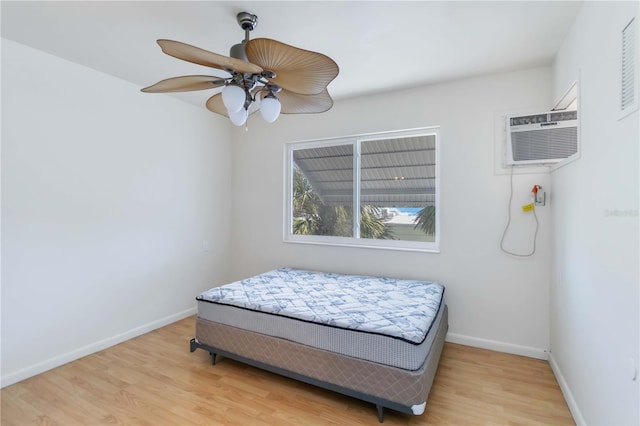 bedroom with ceiling fan, light hardwood / wood-style flooring, and a wall mounted AC