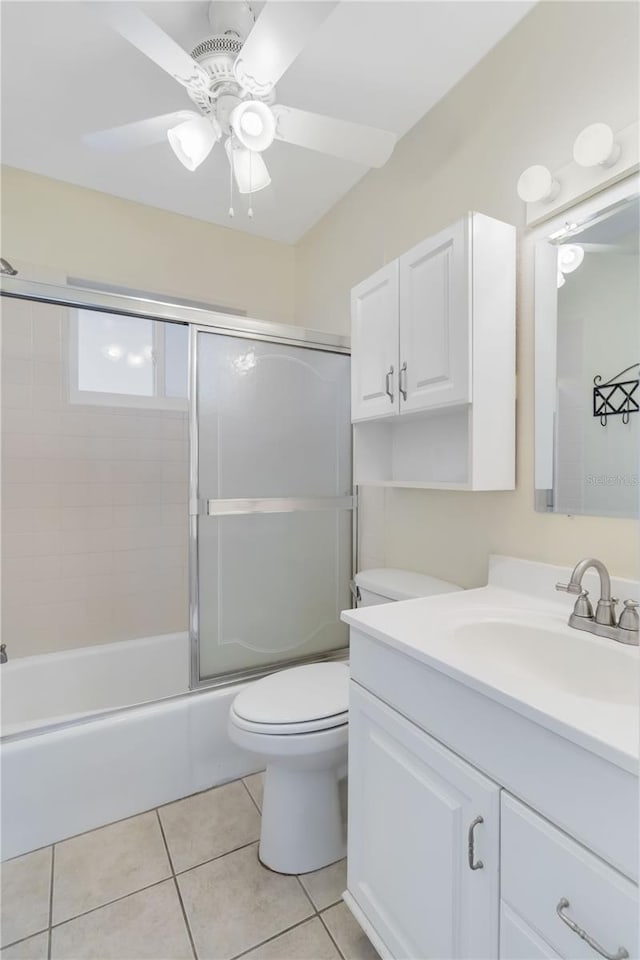 full bathroom featuring combined bath / shower with glass door, tile patterned flooring, vanity, ceiling fan, and toilet